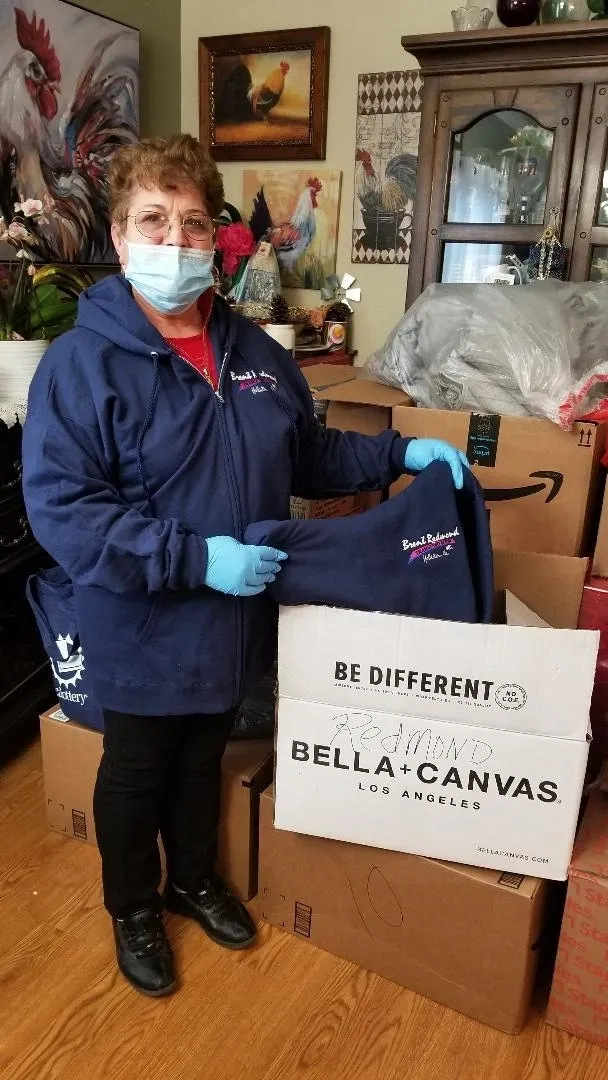 A woman holding up a blue bag in front of boxes.