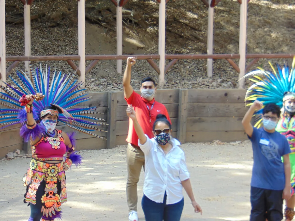 A group of people standing around in front of a wall.