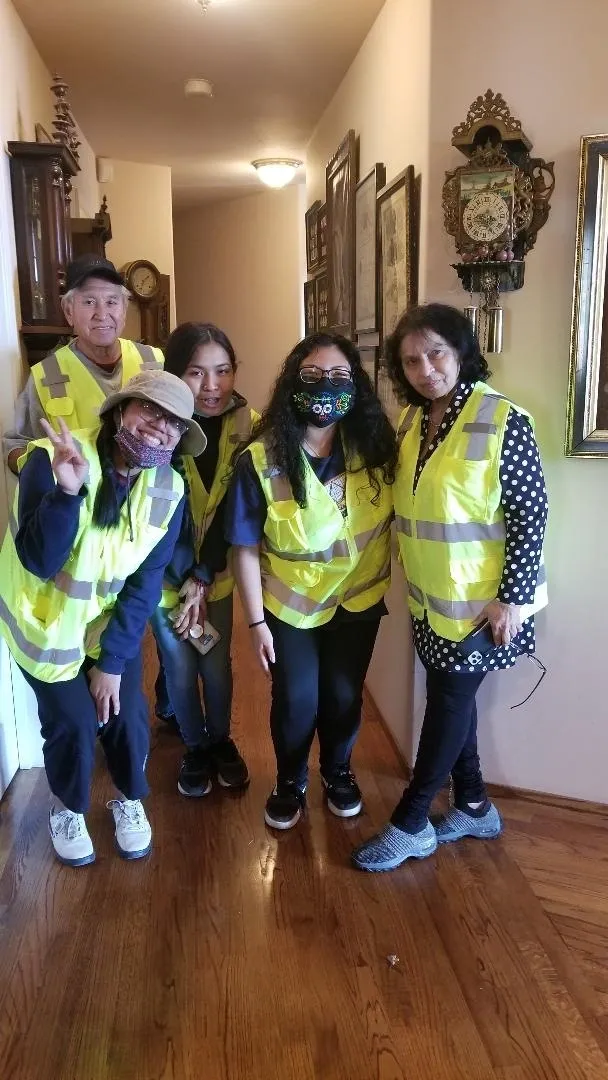 A group of people wearing yellow vests and standing in front of a wall.