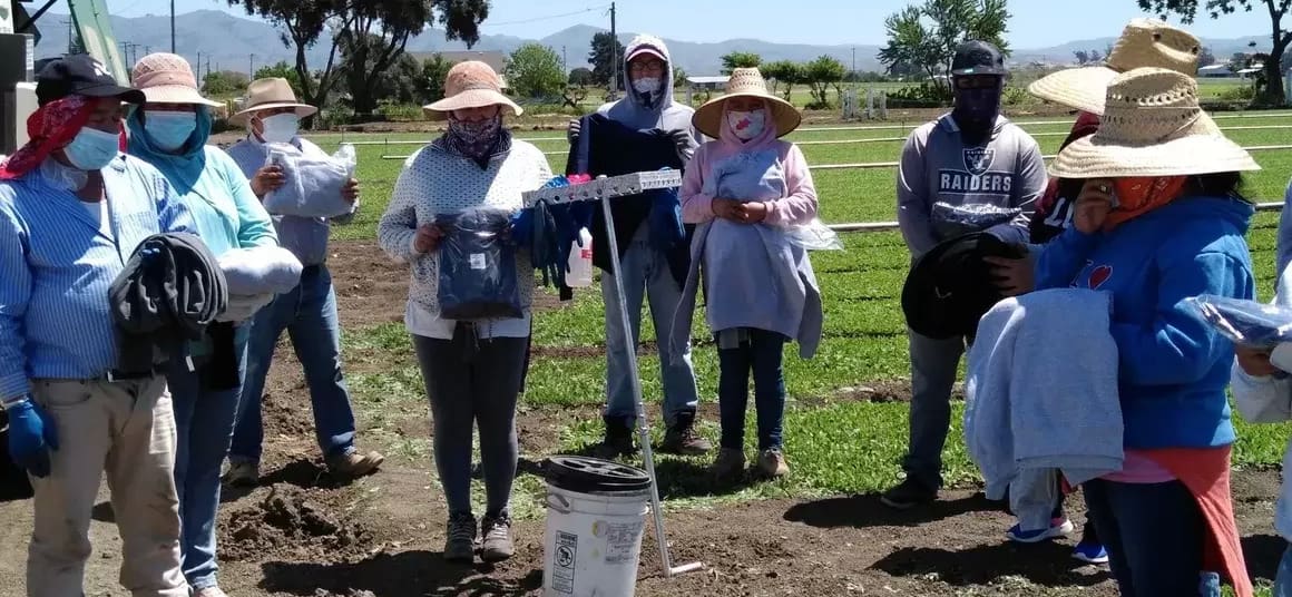 A group of people standing around in the grass.