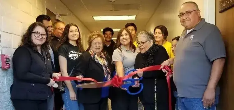 A group of people standing in a hallway holding scissors.