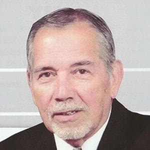 A man in suit and tie with white shirt.