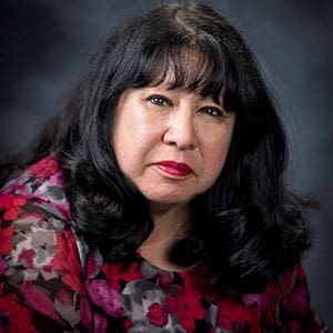 A woman with black hair and red flowers in her dress.