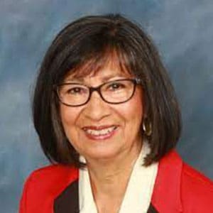 A woman with glasses and black hair wearing a red jacket.