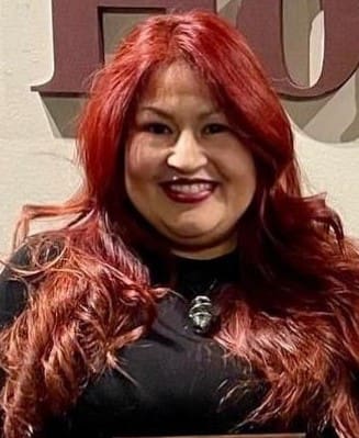 A woman with red hair and black shirt smiling.