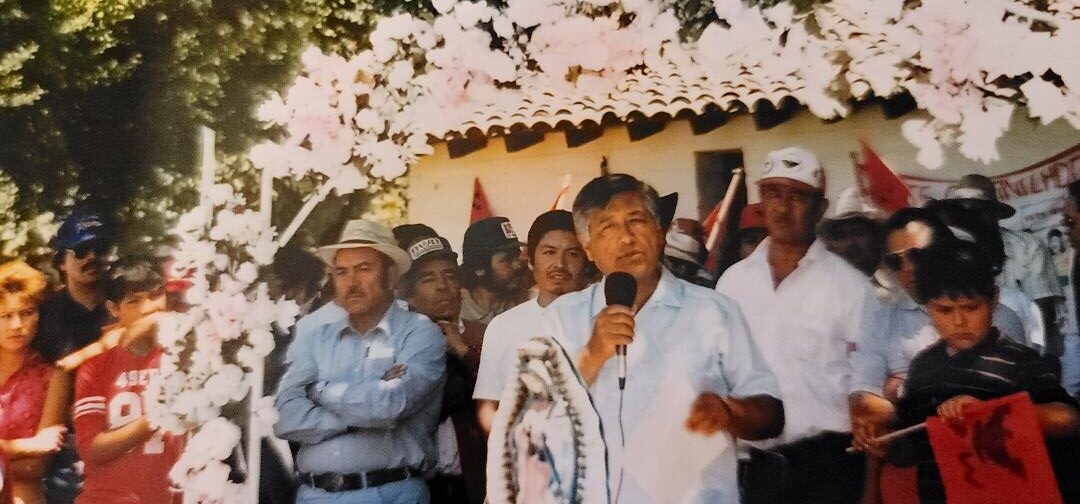 A man is speaking at an event with people behind him.